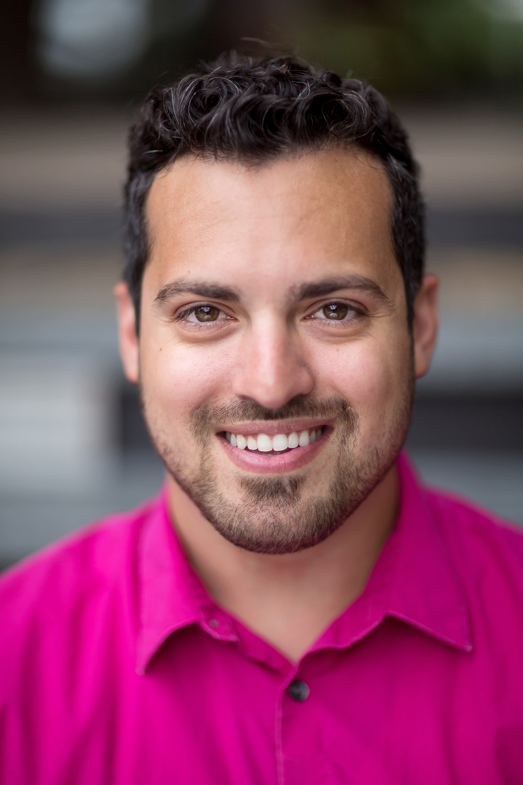 Handsome man in pink shirt smiling.