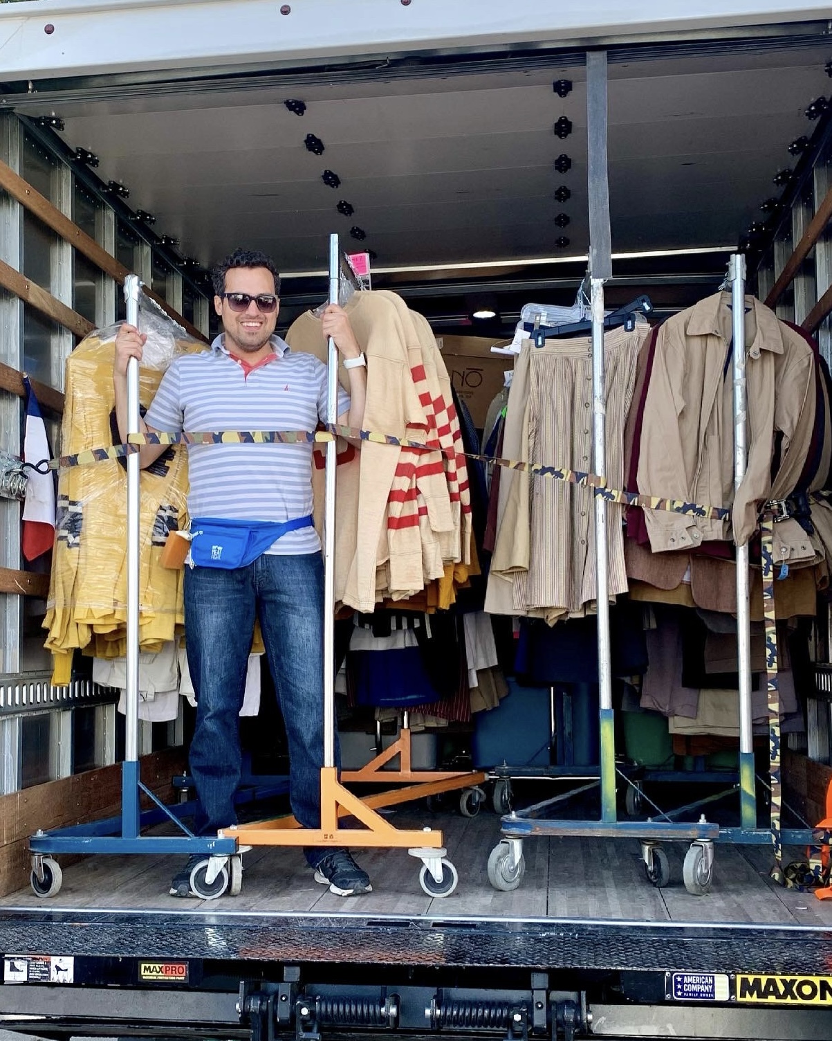 A Costumer in a truck with racks of costumes strapped down behind him.