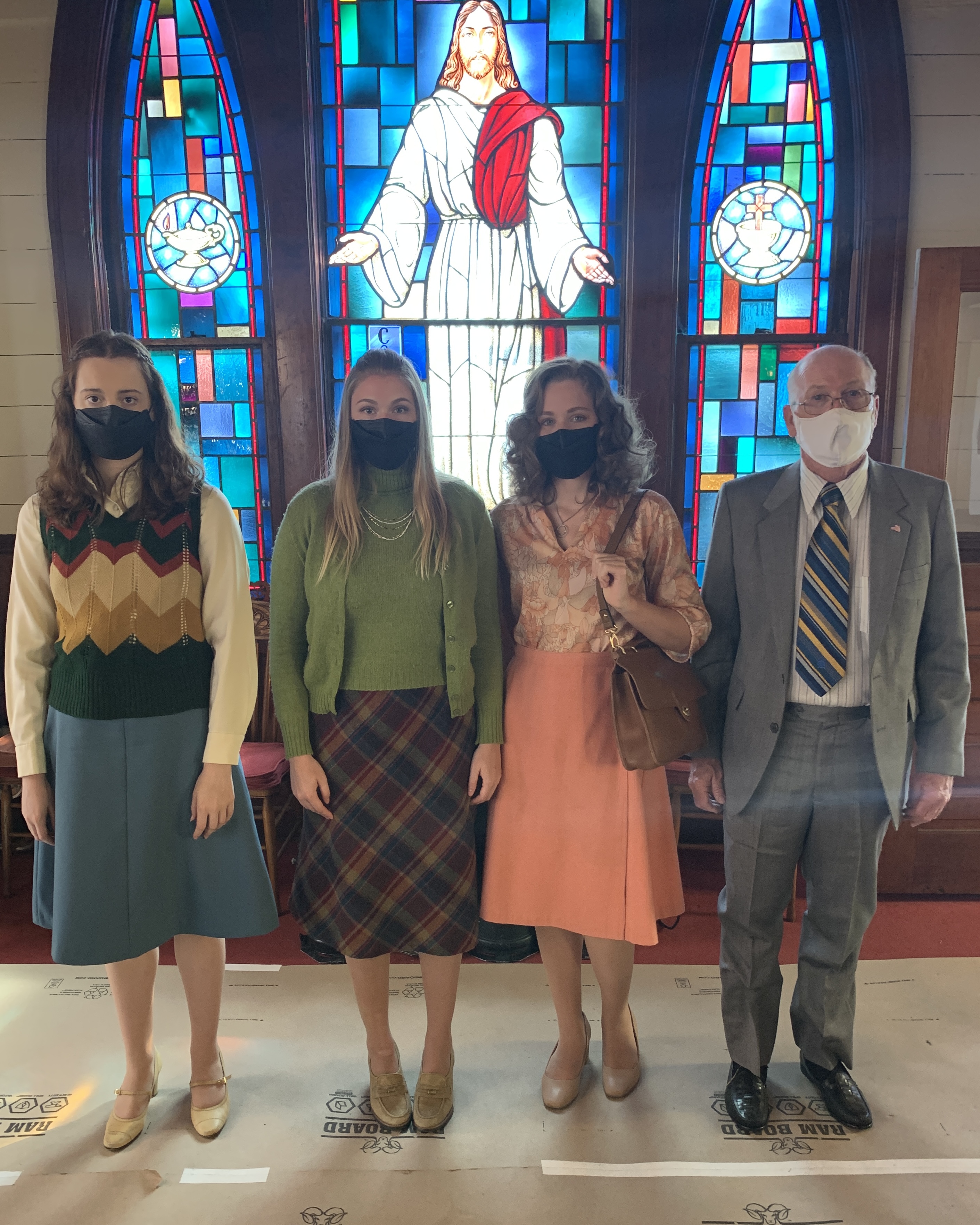 Four background actors dressed as churchgoers on the set of Love & Death.