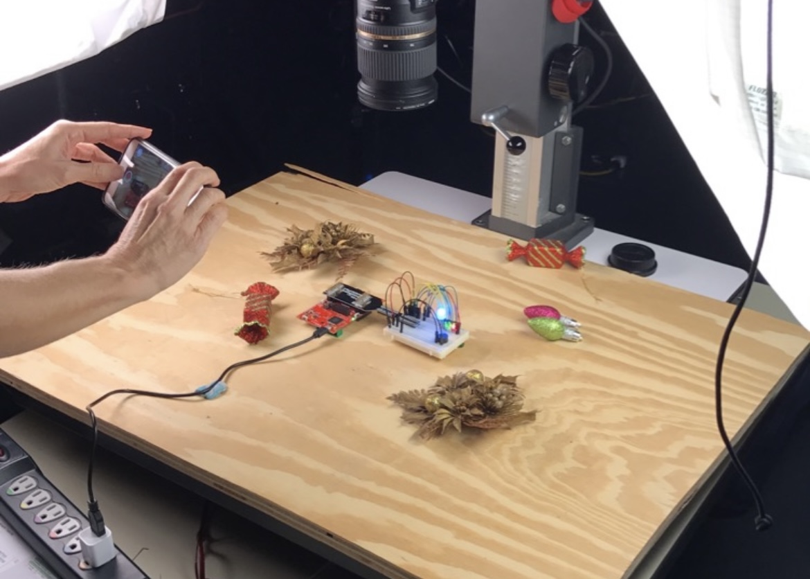 A LEDs on a breadboard in the shape of an x-mas tree on a wooden backdrop.